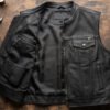 An open leather vest laid flat on a workbench showing multiple pocket types at once — exterior snap chest pocket, interior zippered pocket, and an interior holster-style pocket with reinforced backing. Overhead studio shot, neutral dark background, clear detail on stitching.